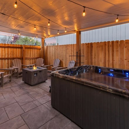 Covered hot tub patio with fire pit and string lights at the Arvada property